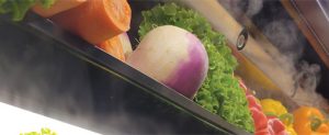 dry fog rolls around carrots, peppers and other produce
